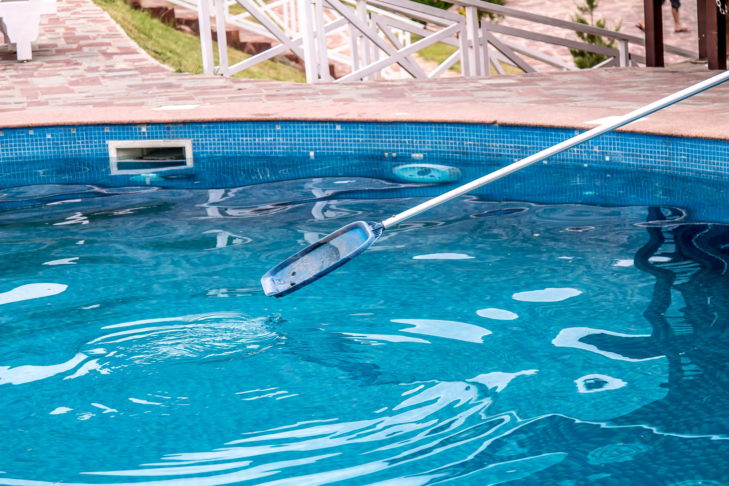 Pool technician cleaning a residential swimming pool in Pensacola FL